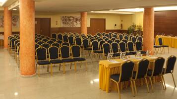 A conference room with rows of chairs and tables, wooden pillars, and a yellow tablecloth.