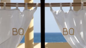 Un balcón con dos camas de madera, ropa de cama blanca y cortinas de gasa.