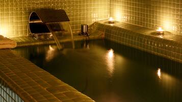 A spa area with a tiled wall, a water feature, and candles.