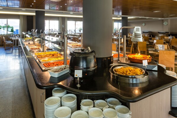 A buffet setup with various food items, a coffee machine, and stacked plates.