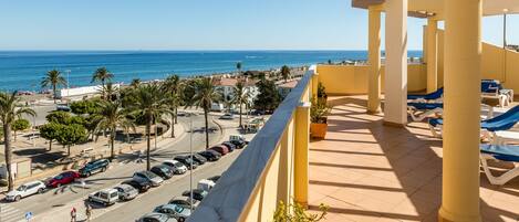 Un balcón con vista a la playa y coches estacionados.