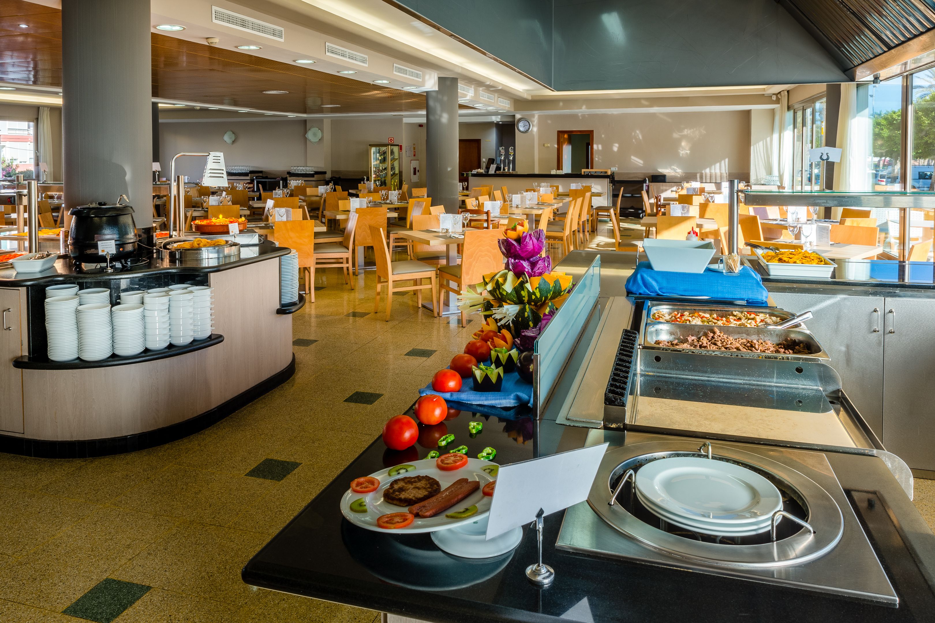 Un'area buffet con diversi cibi, un angolo per insalate e un salotto con tavoli e sedie.