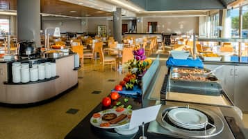 Un'area buffet con diversi cibi, un angolo per insalate e un salotto con tavoli e sedie.