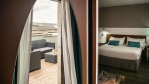 A hotel room with a balcony, a bed with pillows, a nightstand, and a lamp. - ibis Styles A Coruña (A Coruña)
