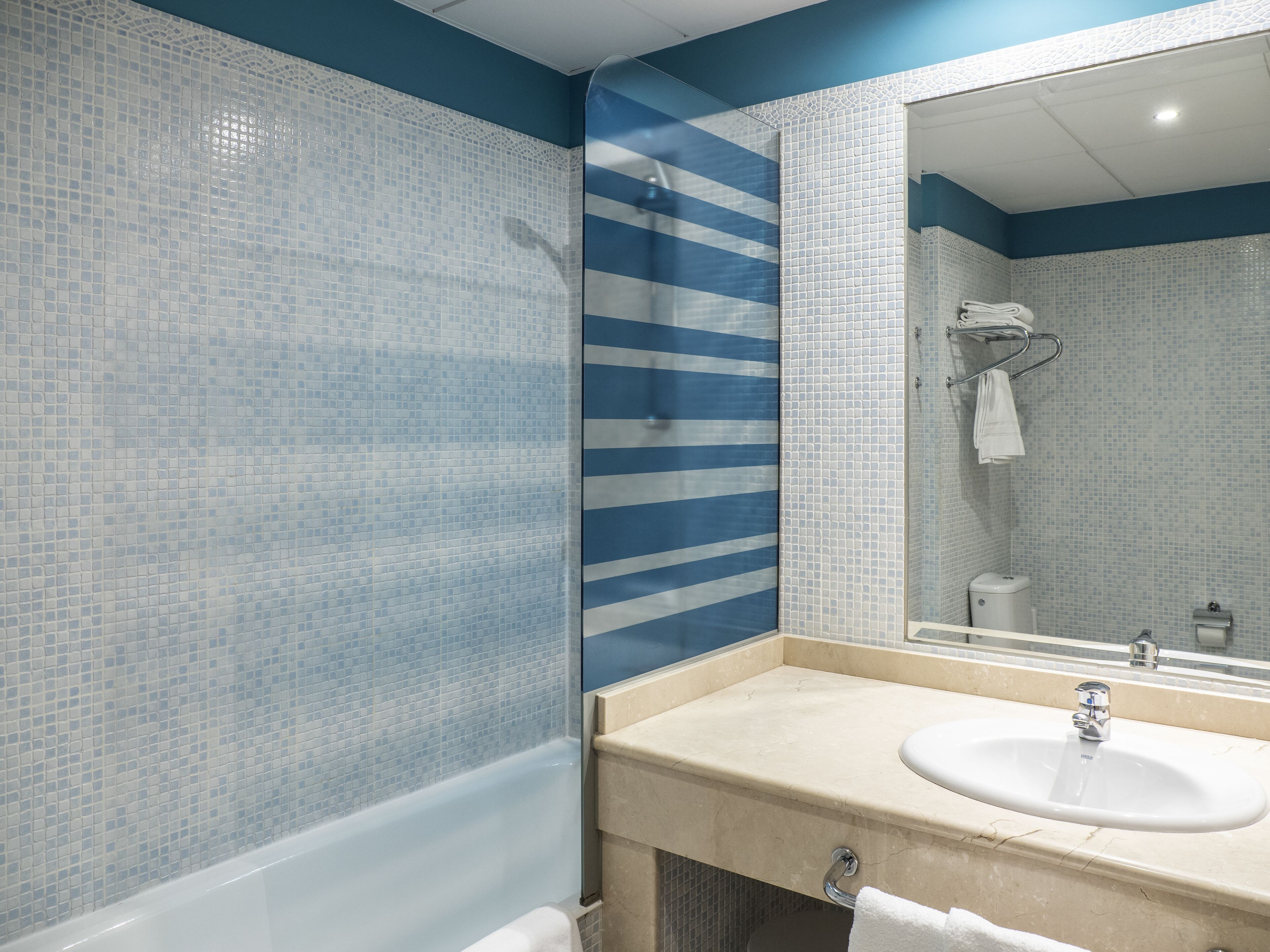 A bathroom with a bathtub, a sink, and a mirror.