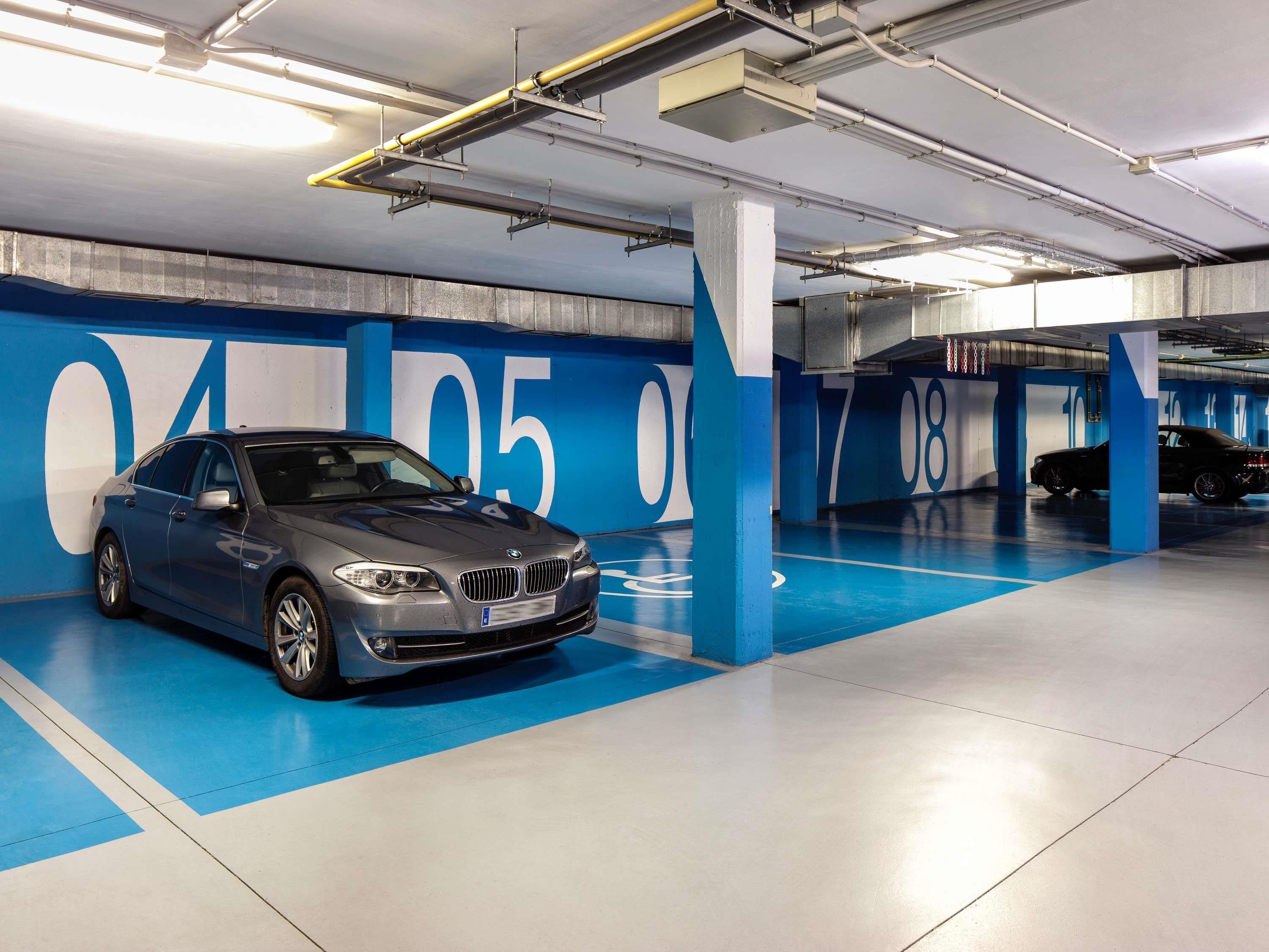 Un aparcament amb un BMW estacionat en una plaça senyalitzada amb números grans.