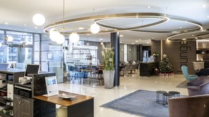 A modern hotel lobby with a reception desk, seating area, and a Christmas tree. - ibis Styles A Coruña (A Coruña)