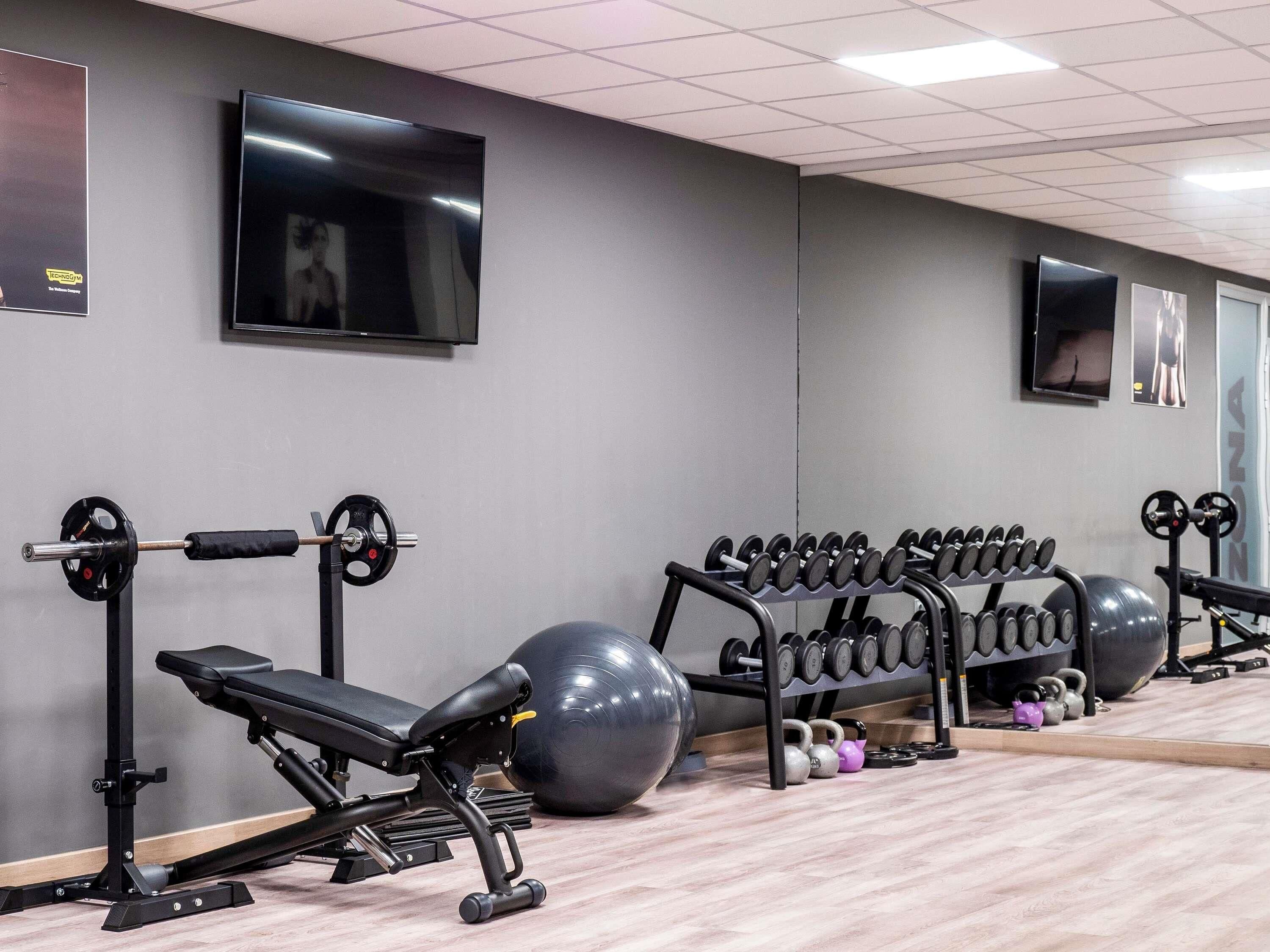 A gym with weightlifting equipment, exercise balls, and dumbbells.