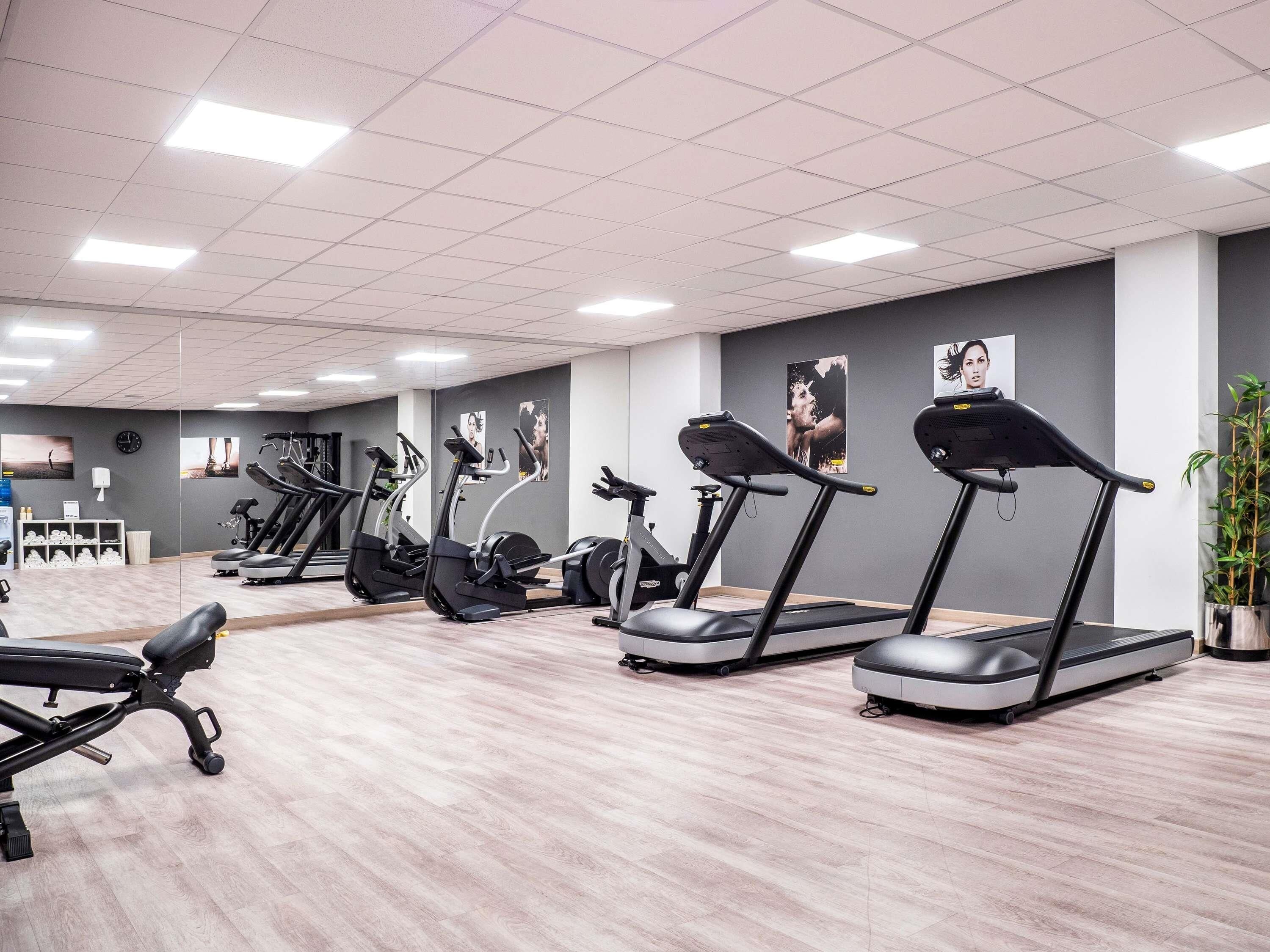 A gym with treadmills, elliptical machines, and a bench.