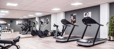 A gym with treadmills, elliptical machines, and a bench.