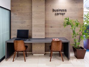 A modern office space with a wooden accent wall, a desk with a computer, two chairs, and a potted plant. - ibis Styles A Coruña (A Coruña)
