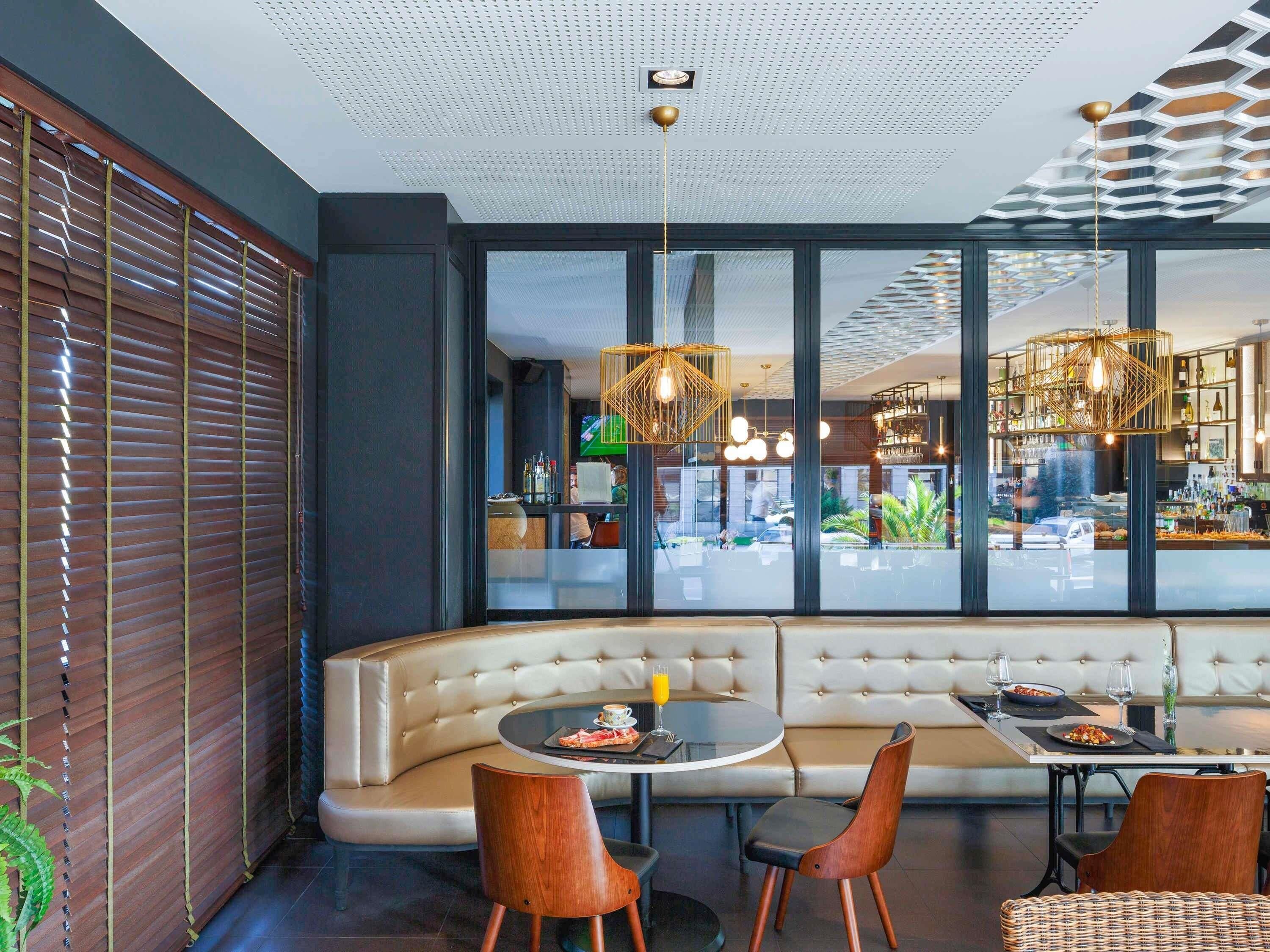 A modern interior with a curved sofa, round tables, and pendant lighting.
