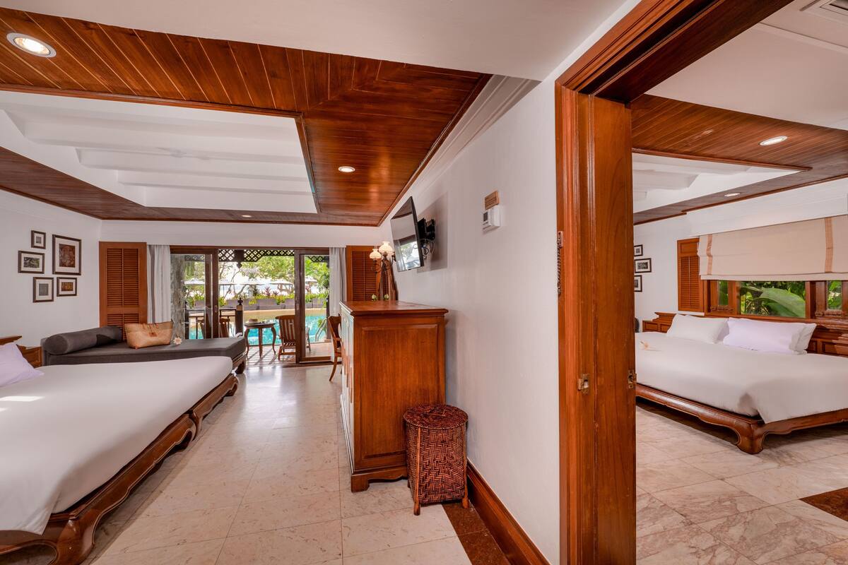 Une chambre d’hôtel avec deux lits, un plafond en bois, une télévision et une vue sur la piscine.