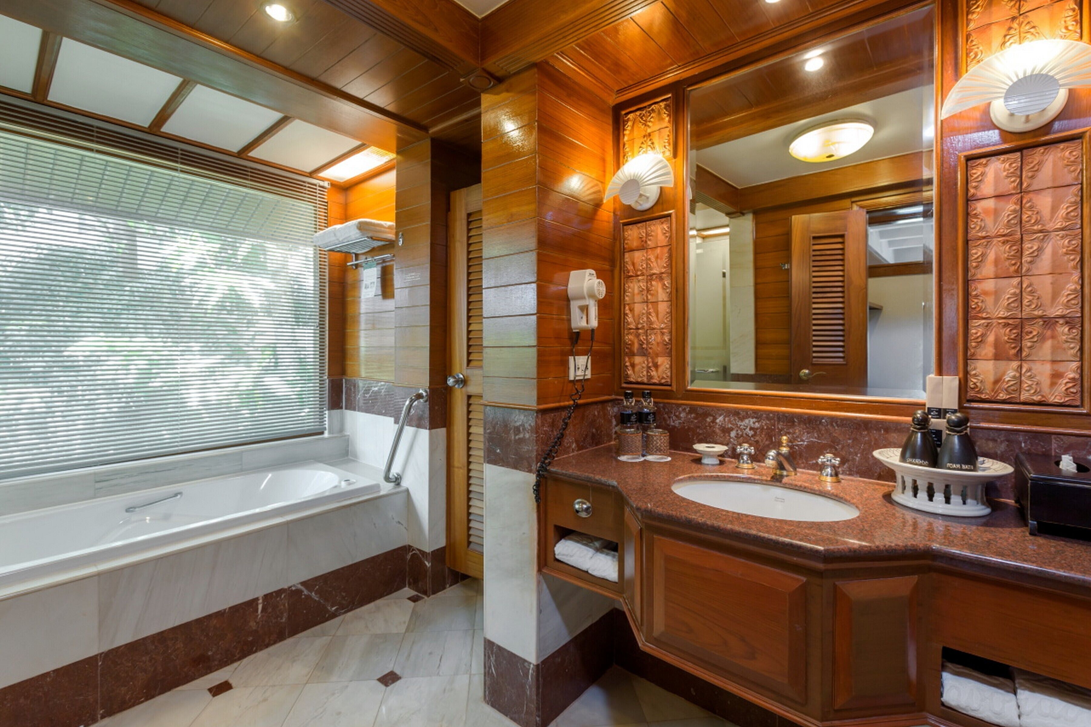 A modern bathroom with a large bathtub, two sinks, and a vanity with a mirror.