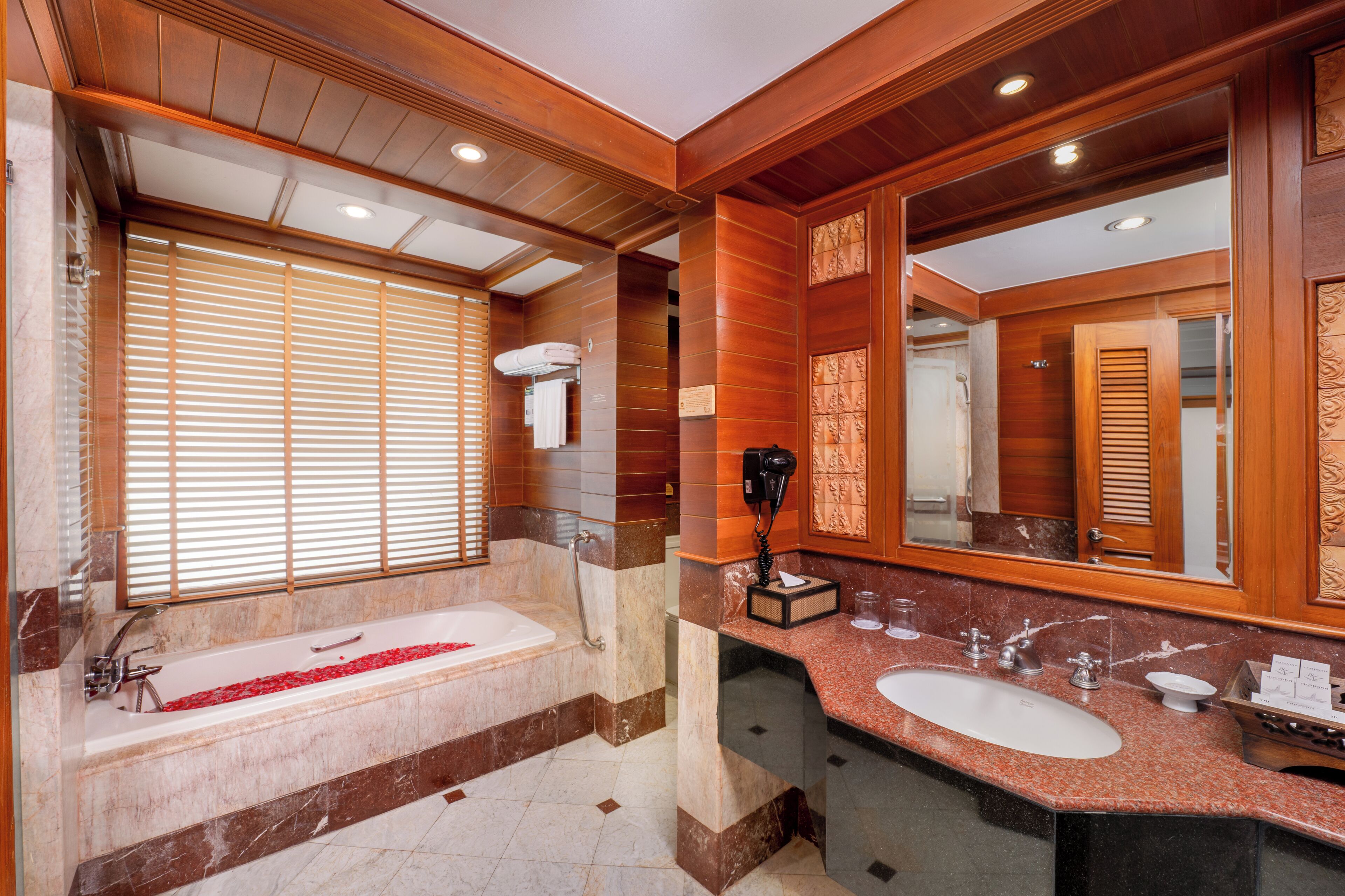 A modern bathroom with a large bathtub, a vanity with a sink, and a large mirror.