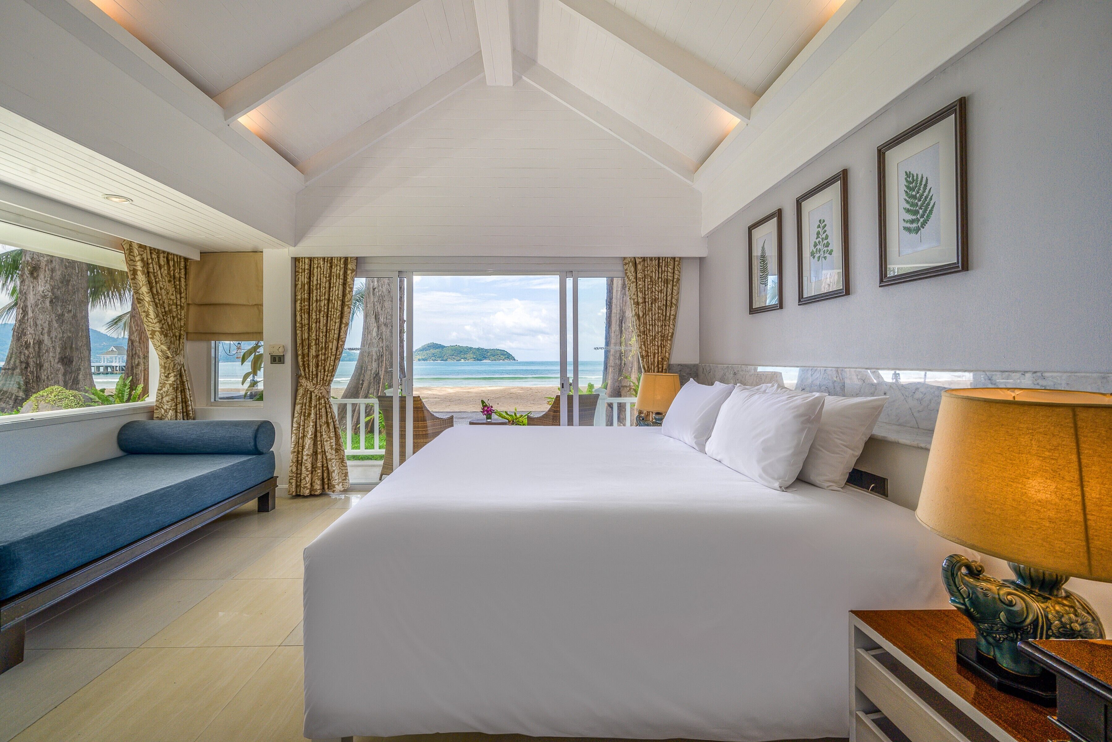 A hotel room with a large bed, a sofa, and a view of the beach.