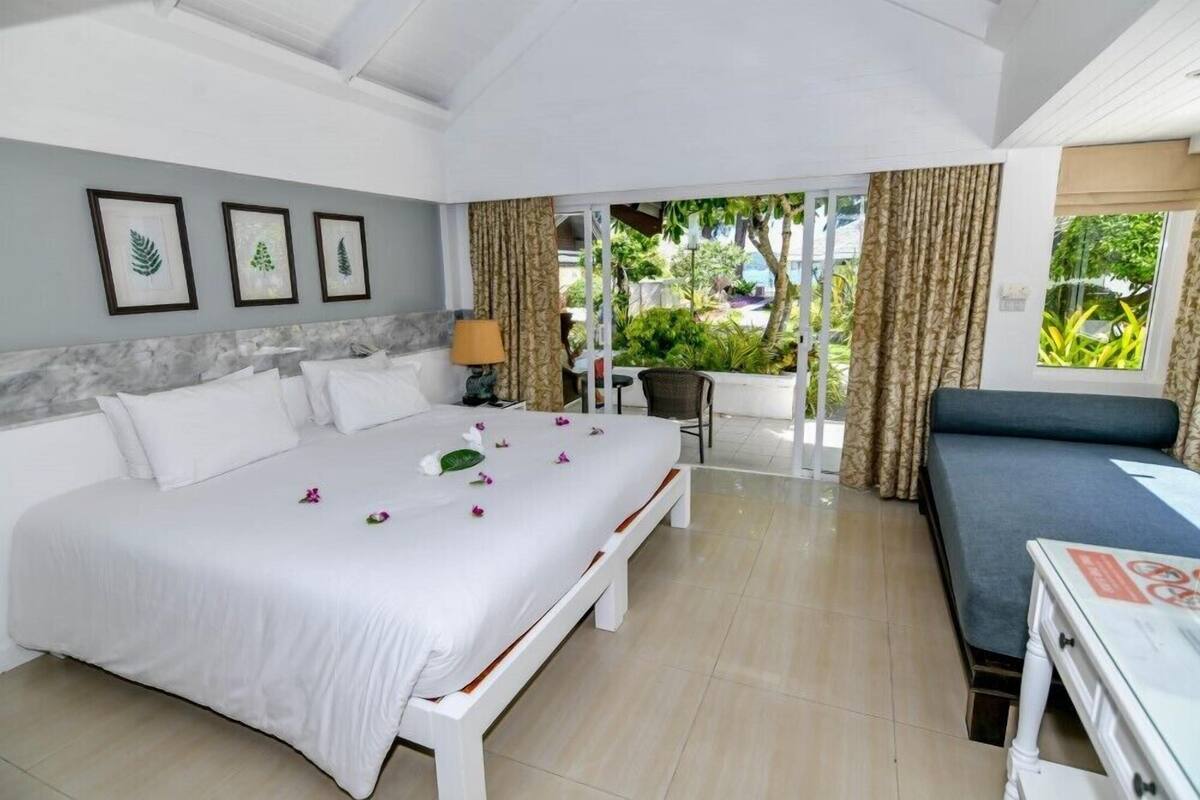 Une chambre d’hôtel avec un grand lit, un canapé, un bureau et une vue sur le jardin.