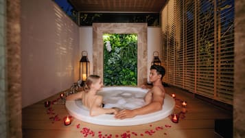 Relax in a serene hot tub surrounded by lush greenery and a stone wall.