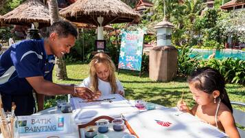 A painting activity setup with a table, painting supplies, and a sign for 'Batik Painting'.