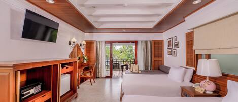 A hotel room with two beds, a TV, a desk with a chair, a small table, and a balcony with a view.