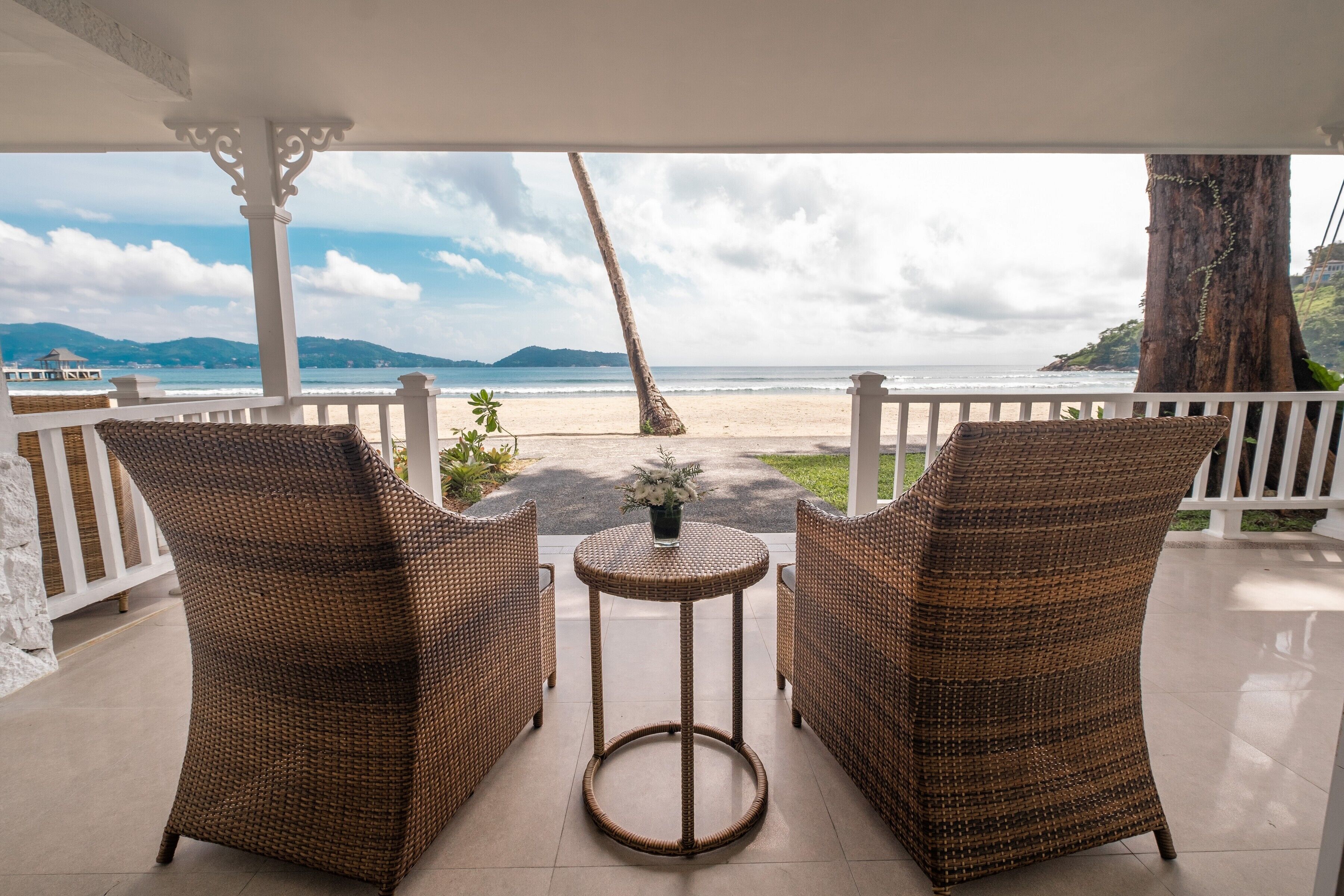 A covered outdoor seating area with wicker furniture and a view of the beach.