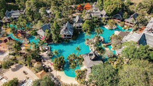 Luchtbeeld van een resort met meerdere gebouwen, een centraal gelegen zwembad en omliggend groen.