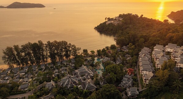 Un village côtier doté de maisons traditionnelles, d’une piscine et offrant une vue sur la mer au coucher du soleil.