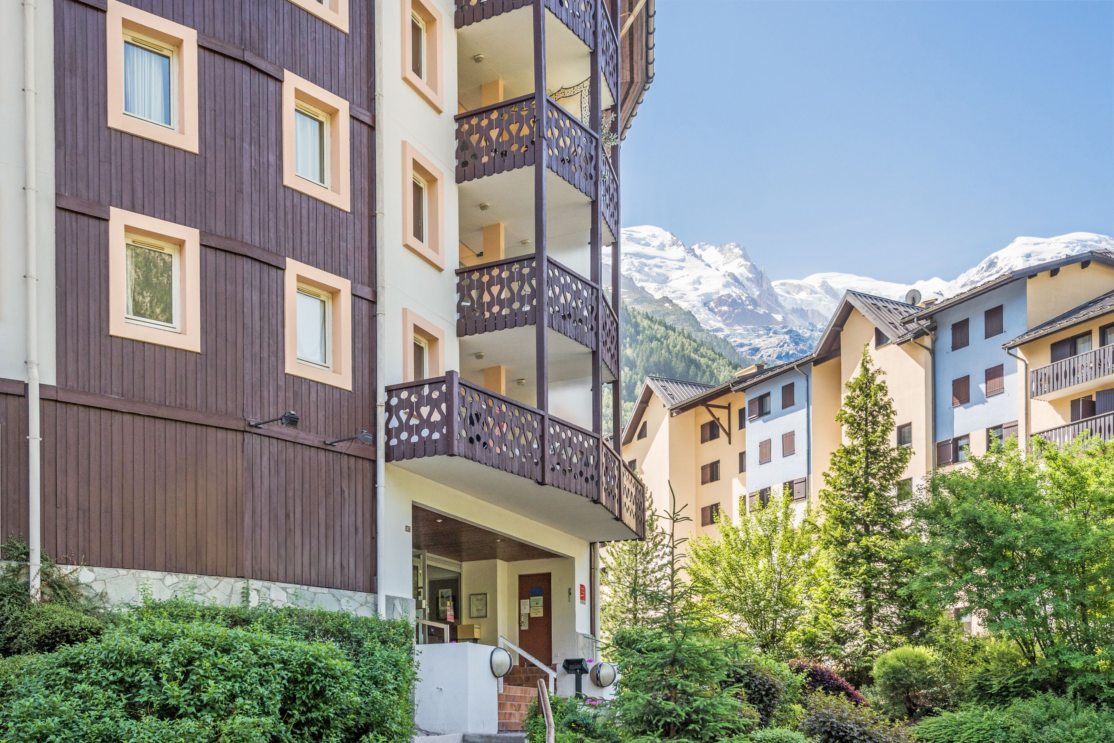 Un hôtel à plusieurs étages, doté de balcons, d’un escalier et surplombant un paysage montagneux.