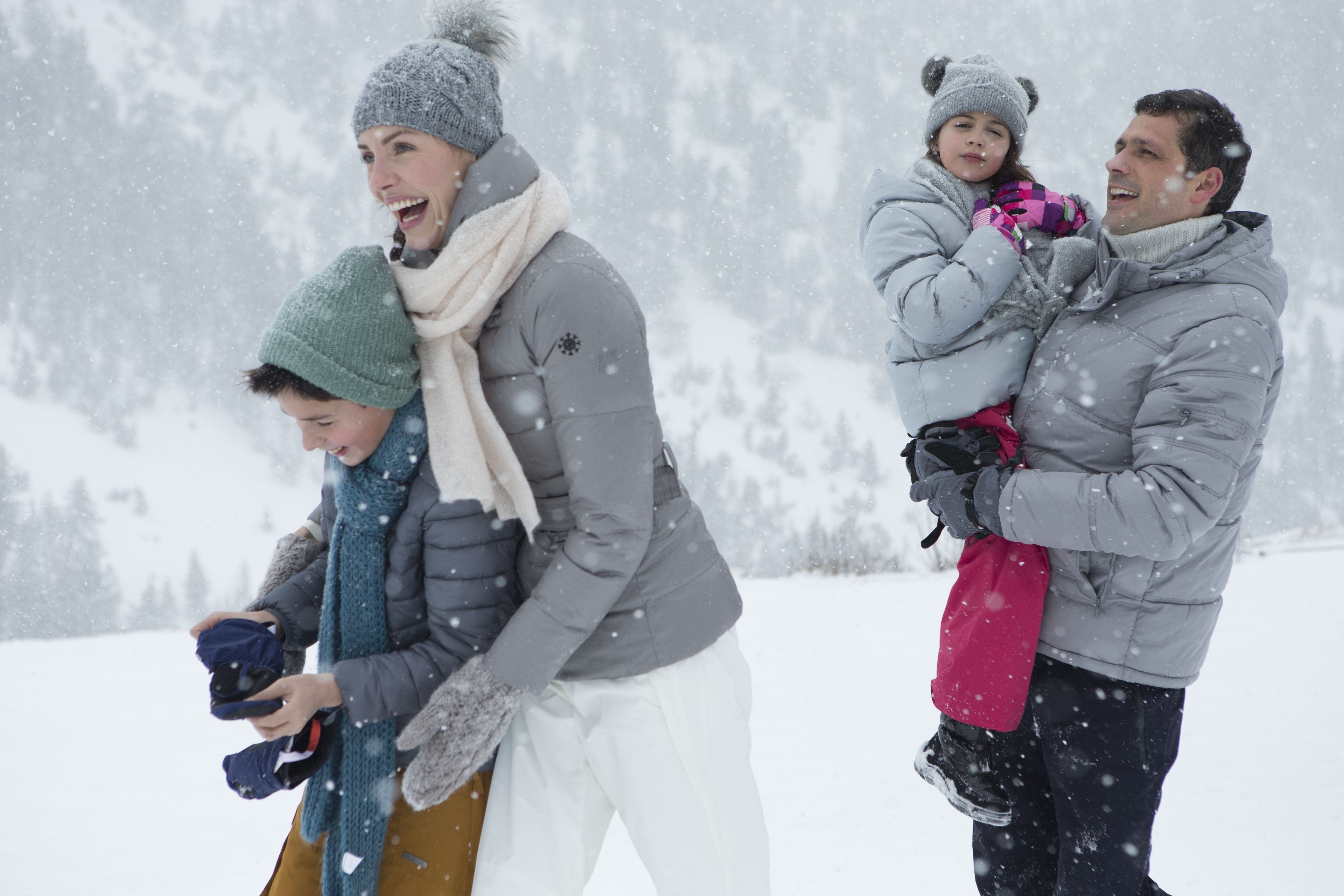 A family in winter clothing standing in a snowy landscape.