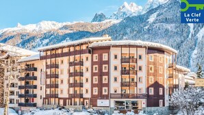 A multi-story hotel with balconies, set against a snowy mountain backdrop. - Résidence Pierre & Vacances Chamonix La Rivière (Chamonix-Mont-Blanc)