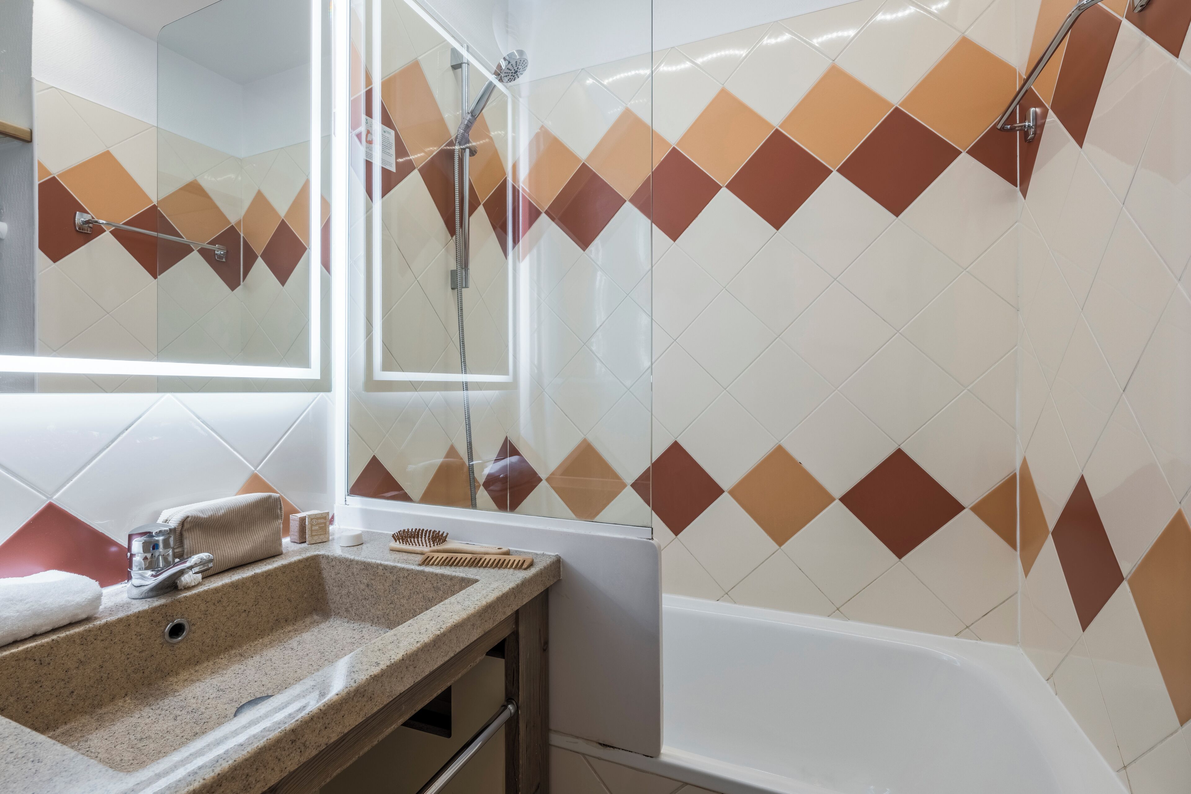 A bathroom with a shower, a sink with toiletries, and a mirror.