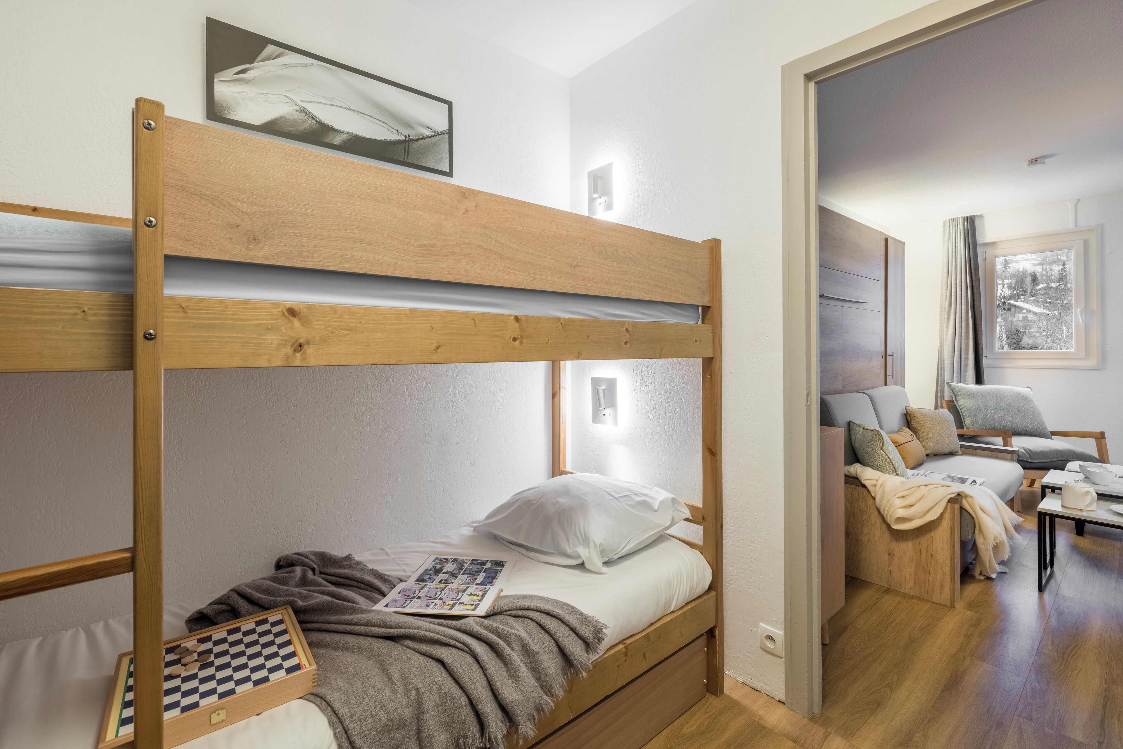 A bunk bed with a checkered board game, a pillow, and a blanket on the lower bunk.