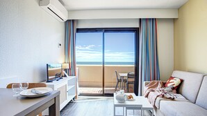 A hotel room with a balcony, a dining area, a sofa, and a TV. - Pierre & Vacances Résidence Les Balcons de Collioure (Collioure)