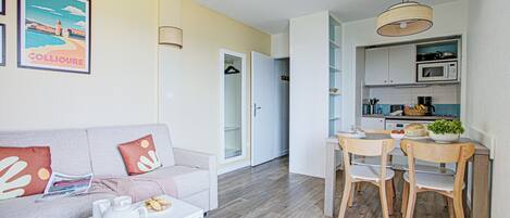 A compact living space with a sofa, coffee table, and dining area.