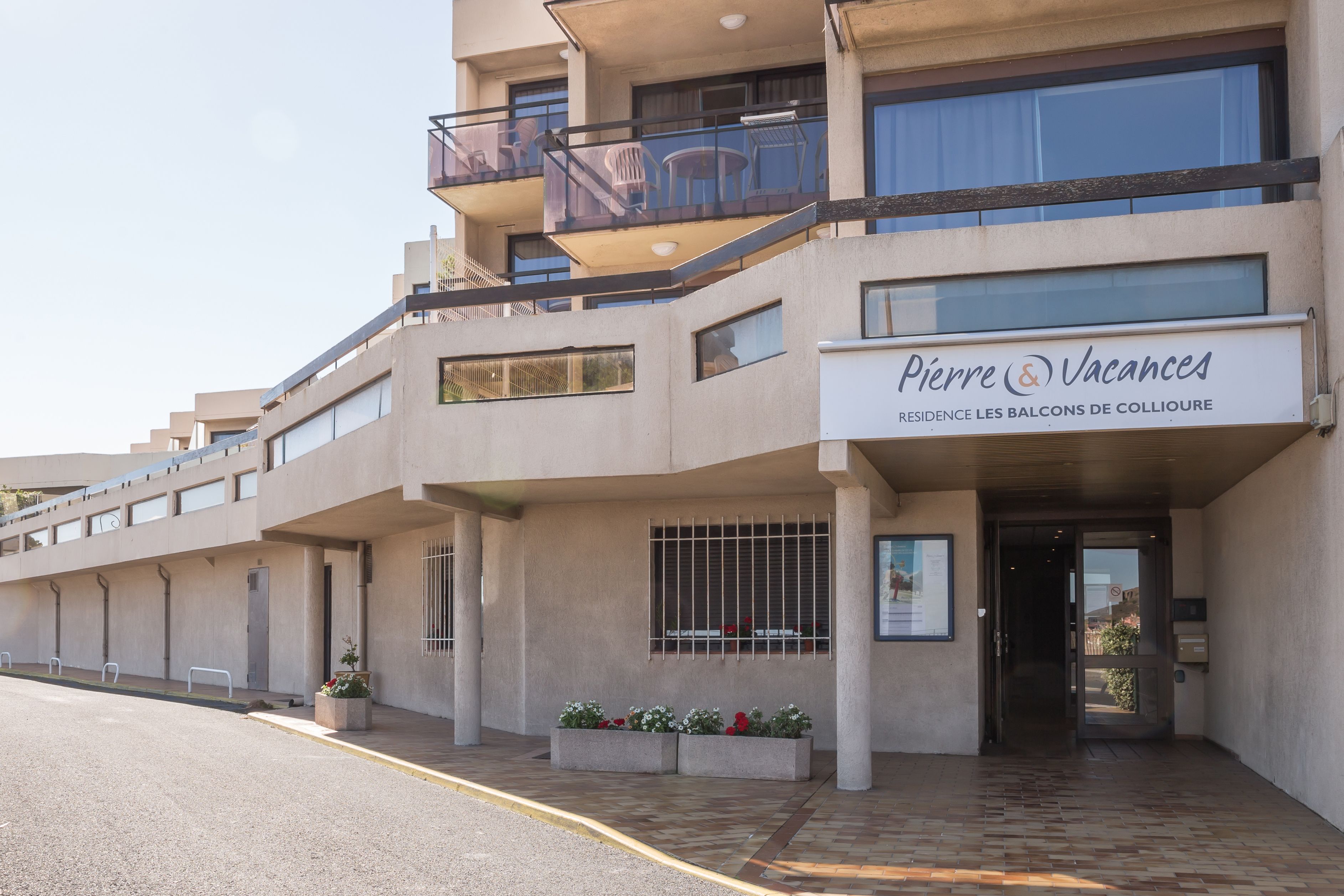 Un hôtel à plusieurs étages, avec une enseigne indiquant « Pierre & Vacances » et des balcons aménagés avec du mobilier d’extérieur.