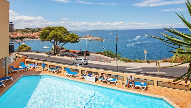 Zona de piscina con sillones de descanso y vistas al mar.