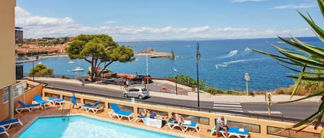 Un espace piscine avec des chaises longues et vue sur la mer.