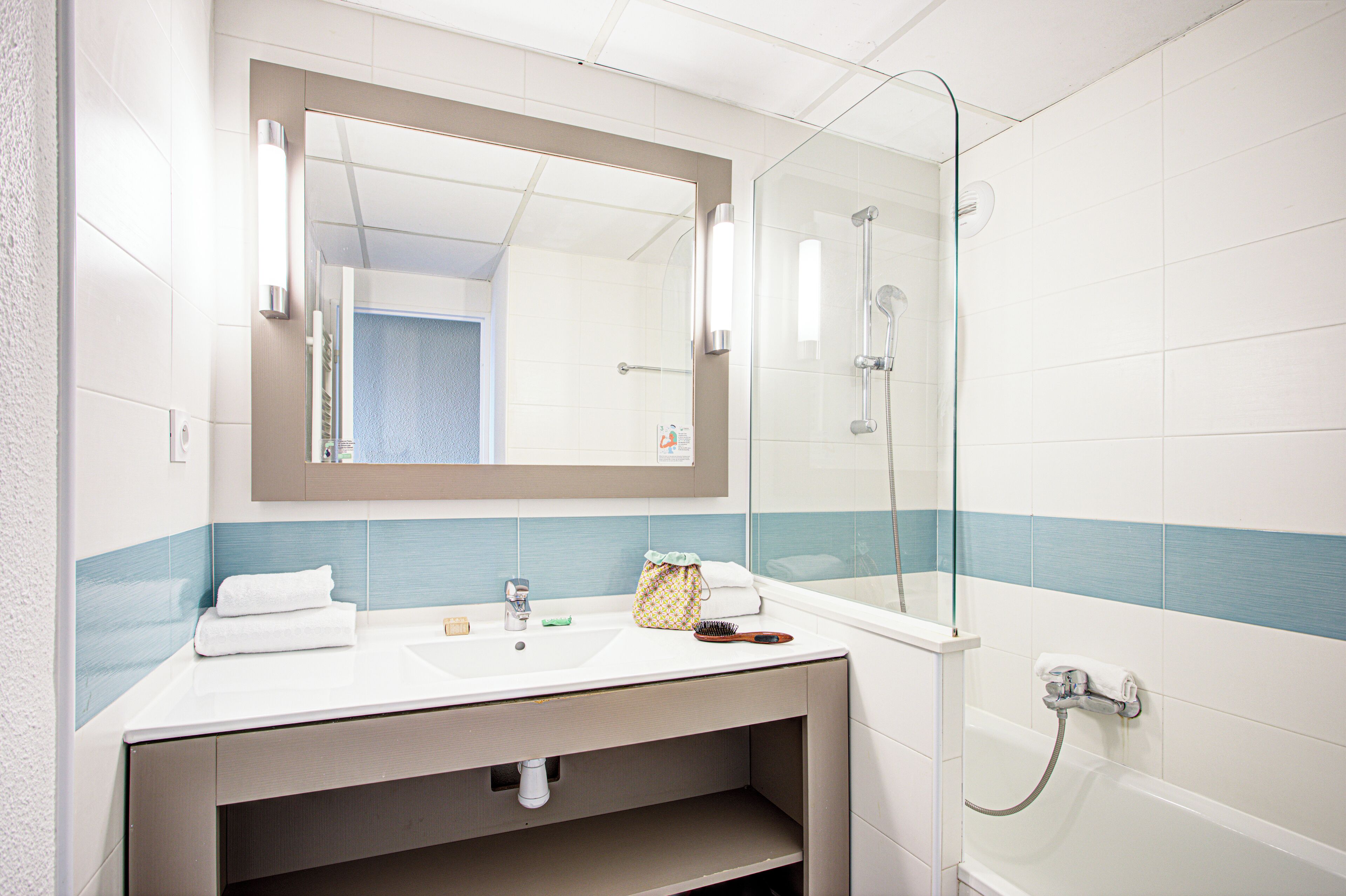 A bathroom with a white sink, mirror, and glass shower enclosure.