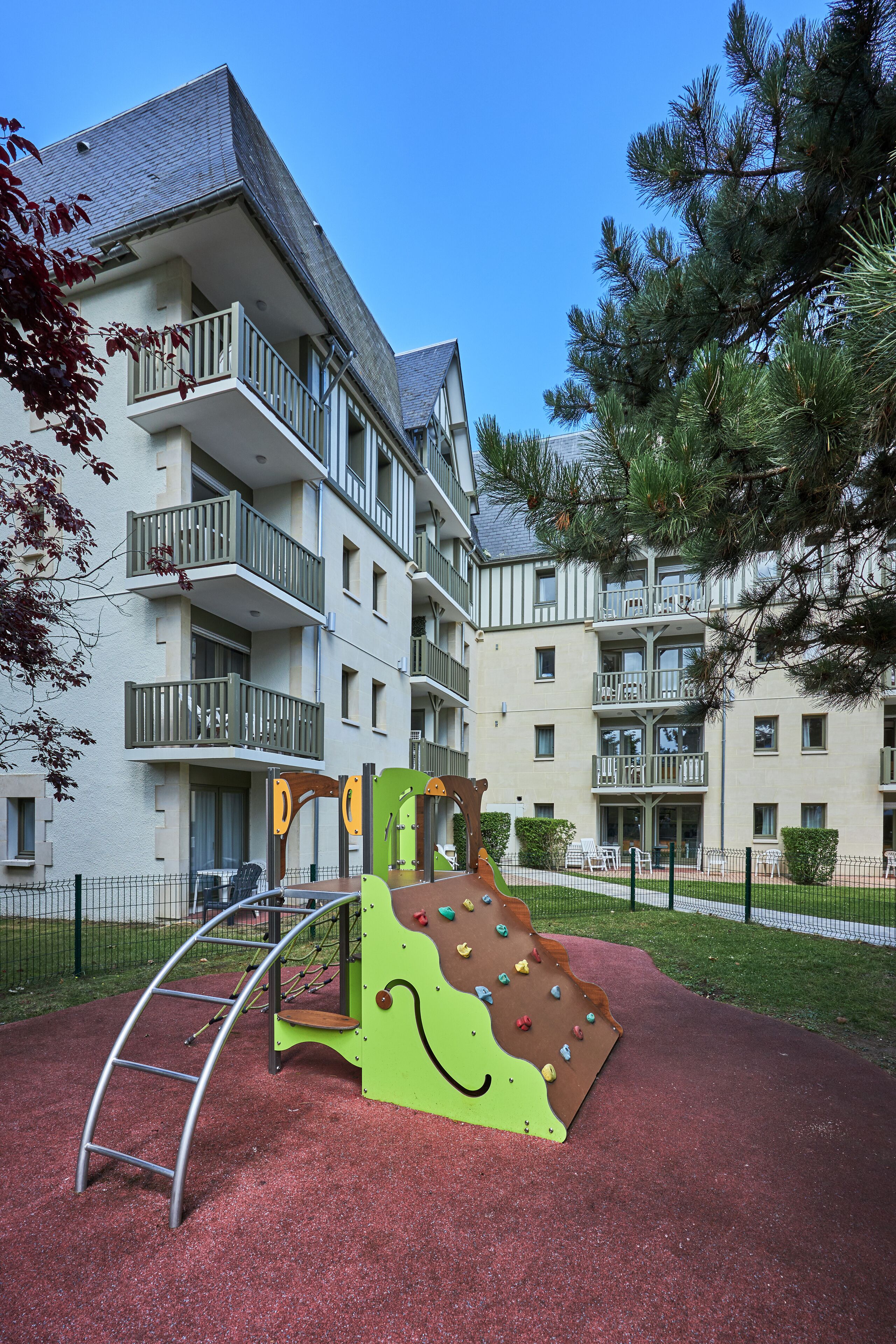 A playground with climbing structures and a slide, surrounded by apartment buildings.