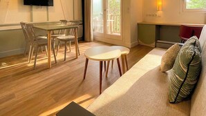 Una habitación con una mesa de comedor, sillas, un sofá, un televisor y un puerta corredera que da a un área exterior.