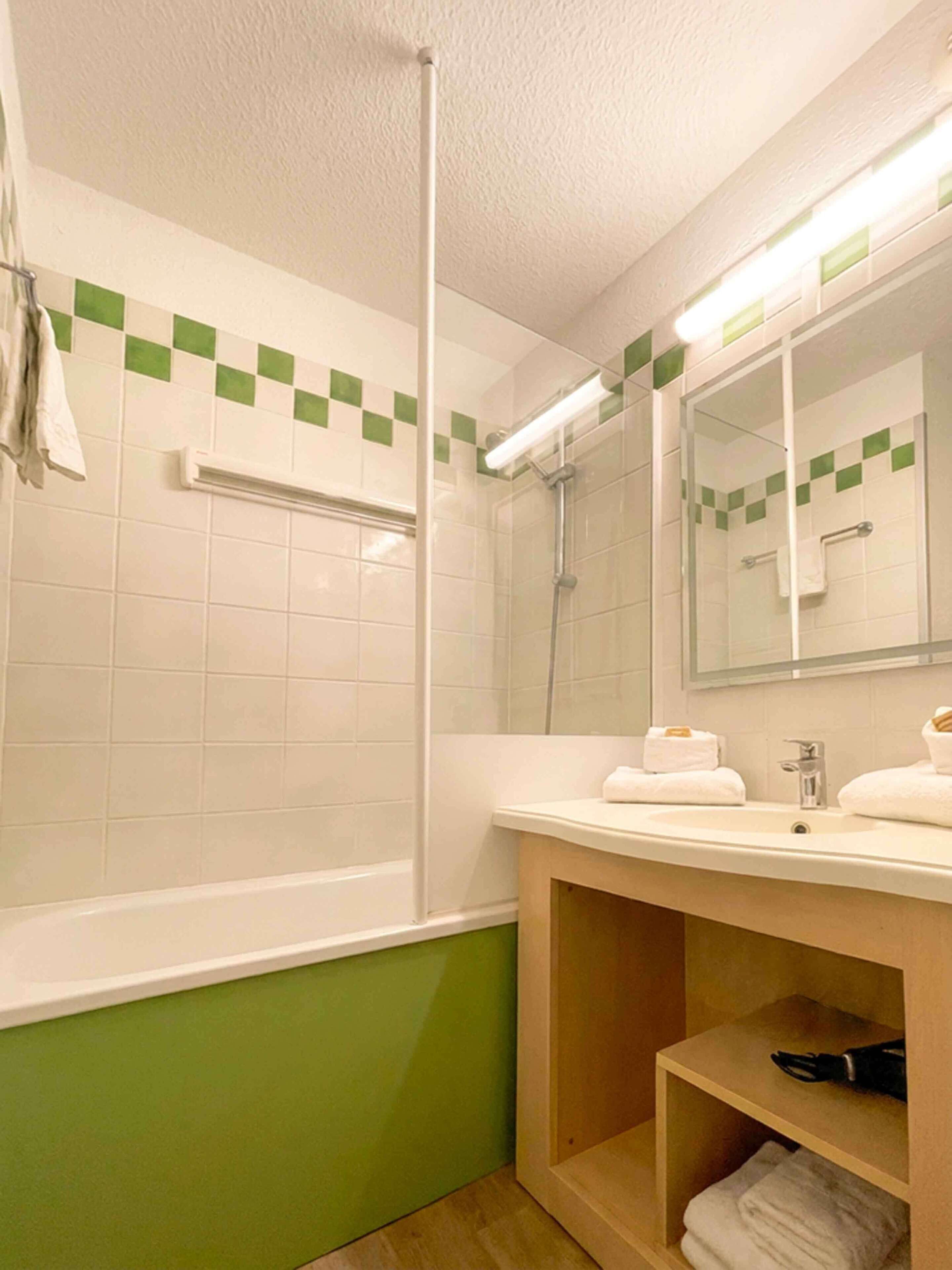 Une salle de bain avec une douche, un lavabo avec un miroir et un porte-serviettes.
