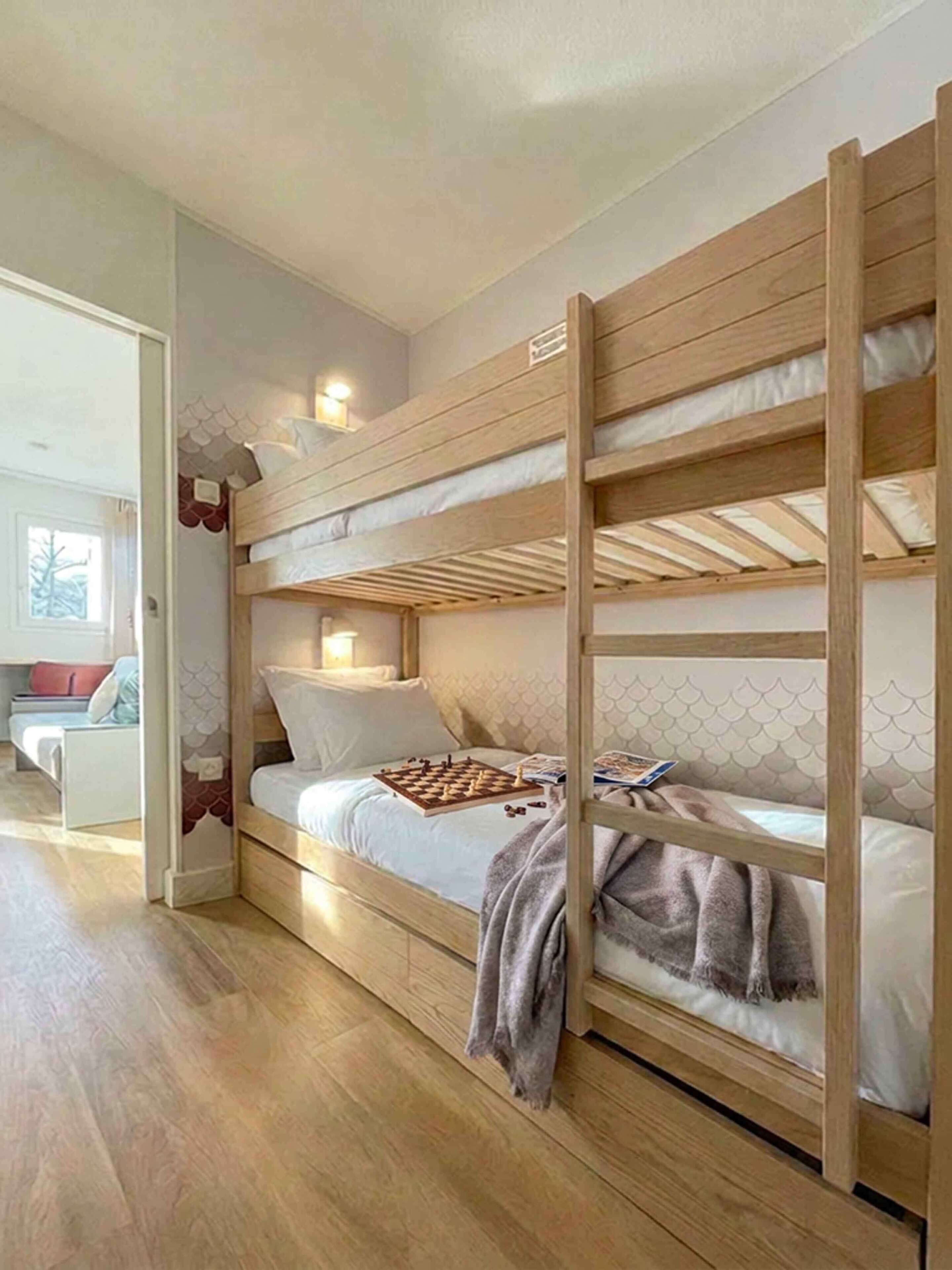 Una cama individual con estructura de madera, una mesita de noche y una silla en la habitación contigua.