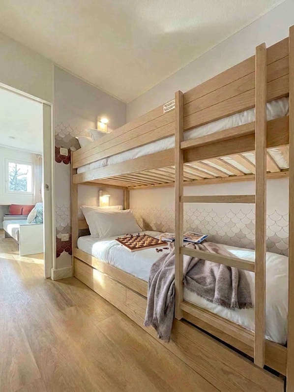 Una cama individual con estructura de madera, una mesita de noche y una silla en la habitación contigua.