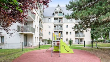 Explore the adjacent playground with a green slide and climbing structure, surrounded by a park with grass and trees.