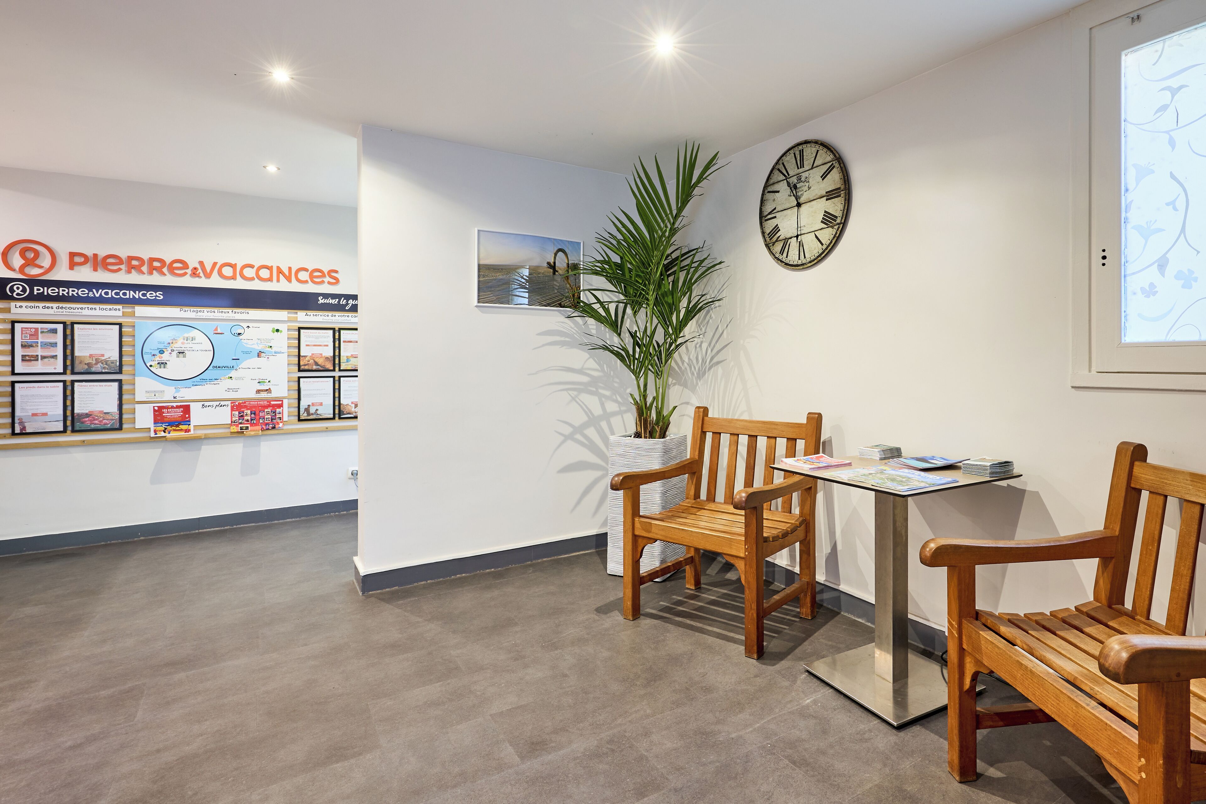 A reception area with a wooden bench, a clock, and a potted plant.