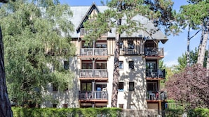 Un edificio de varios pisos con balcones, rodeado de árboles y vegetación.