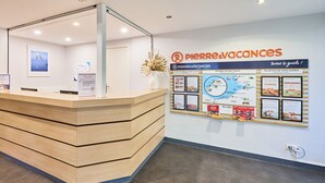 Un mostrador de recepción con detalles de madera y una pared de vidrio. Se observa un letrero adherido a la pared con el logotipo 
