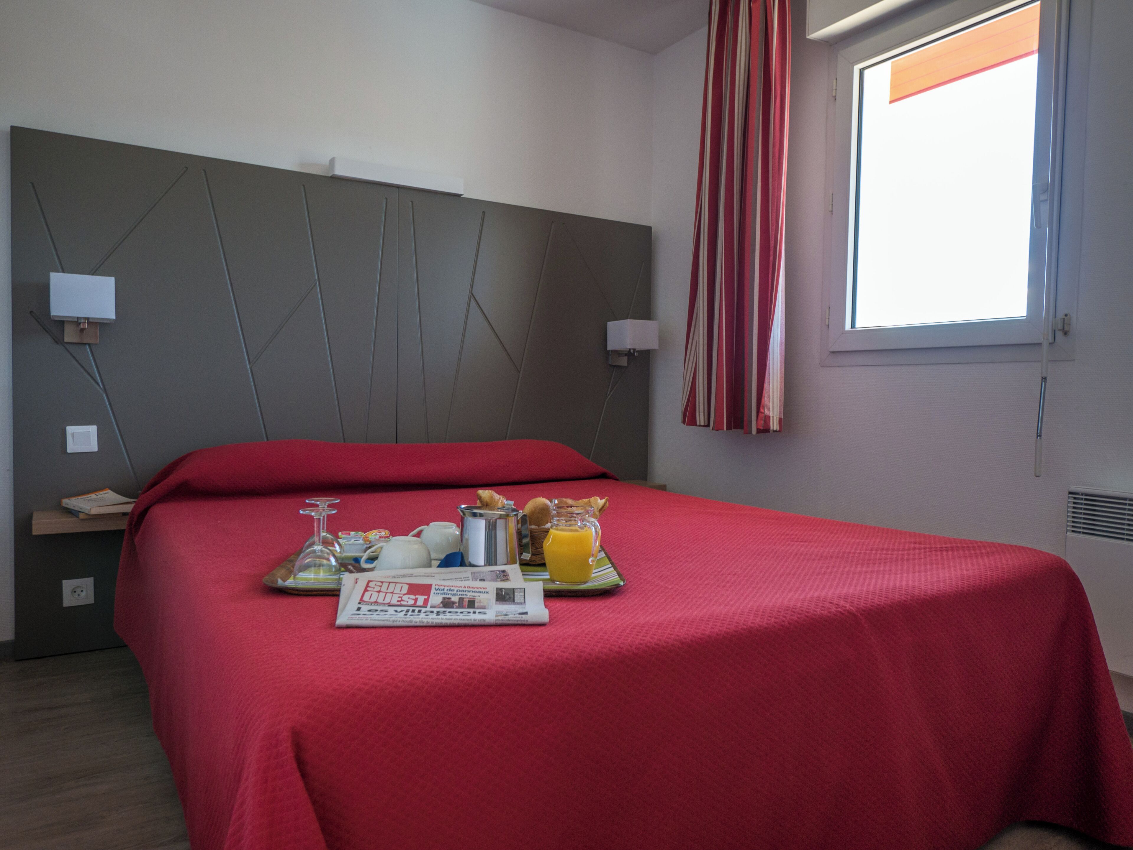 Habitación de hotel con cama, bandeja de desayuno y ventana con cortinas.
