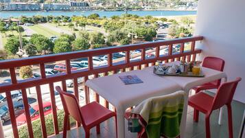 Un balcón con una mesa lista para el desayuno, con vista a un estacionamiento y un lago.