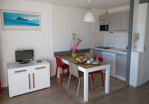 A compact kitchen with a microwave, a small refrigerator, and a dining area with a table and chairs.